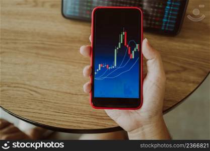 Investor holding phone and looking at candlestick chart suitable for Stock market forex or cryptography trading financial investment graphs Finance Economy trends Trading Stock Concept