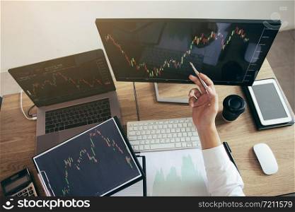 Investor man analyzing the graph of the stock market using a pen pointing to the computer screen.