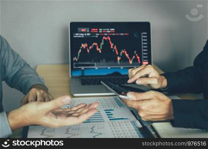 Investors man are using digital tablets to find information of company that are analyzing stocks market together with colleagues at the office.