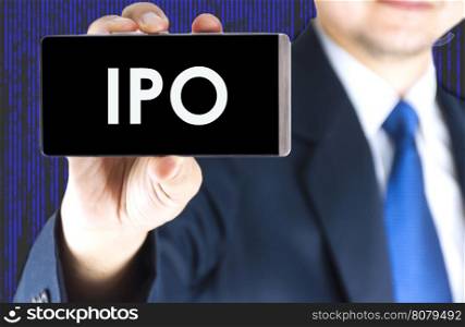 IPO, Initial Public Offering, word on mobile phone screen in blurred young businessman hand and digital technology background, business concept