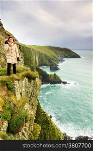 Irish atlantic coast. Woman tourist standing on rock cliff by the ocean Co. Cork Ireland Europe. Beautiful sea landscape natures beauty.