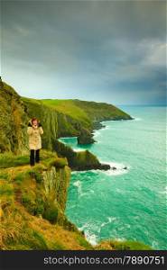 Irish atlantic coast. Woman tourist standing on rock cliff by the ocean Co. Cork Ireland Europe. Beautiful sea landscape beauty in nature.