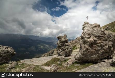 Iron cross in the rock near Lac De Nino in Corsica and dark clouds and mountains in the background