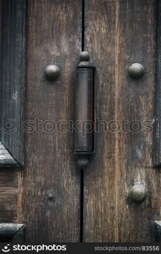 iron door hinge on old brown wooden doors, close up
