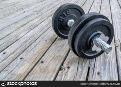 iron dumbbell on a grunge wooden deck - fitness concept