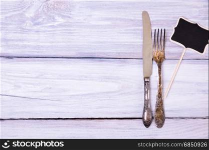 Iron fork and knife on a white wooden surface, empty space. Iron fork and knife on a white wooden surface