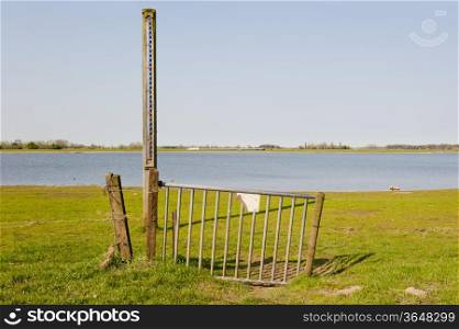 Iron gate with the scale of the waterlevel in the floodplains of the river IJssel at low tides, the Netherlands