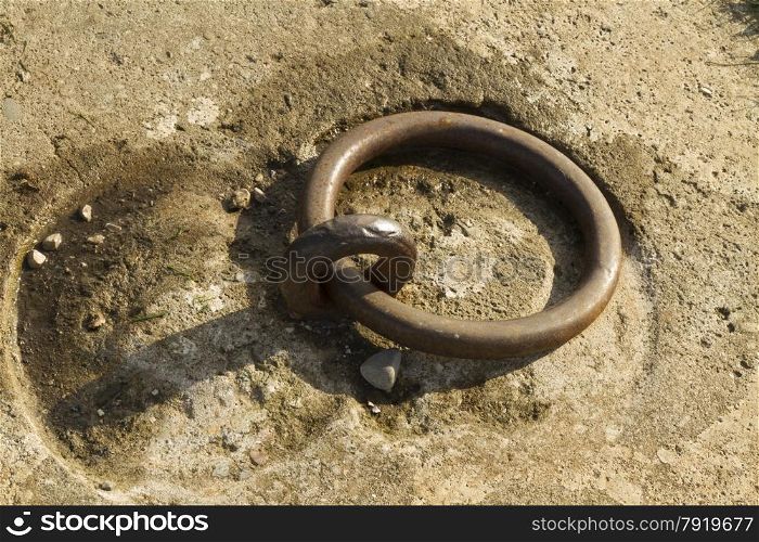 Iron mooring ring set in concrete. Closeup.