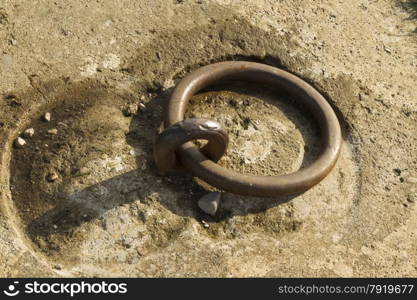 Iron mooring ring set in concrete. Closeup.