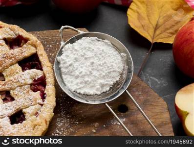 iron strainer with powdered sugar and baked round cake
