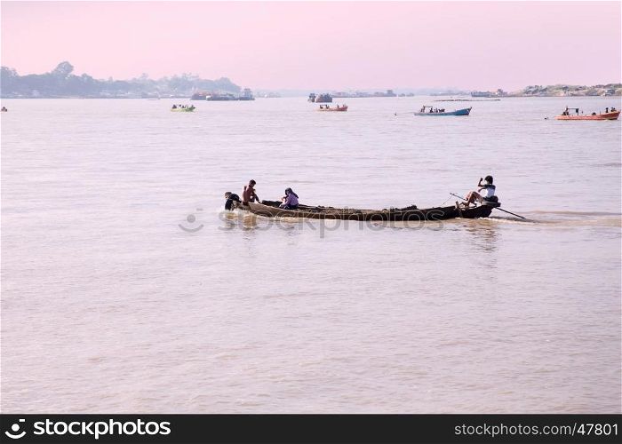 IRRAWADY RIVER, MYANMAR - November 17, 2015: Boats on the Irrawaddy River at sunrise. The Irrawady river is a river that flows from north to south through Myanmar and is the most important waterway