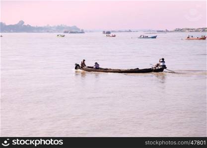 IRRAWADY RIVER, MYANMAR - November 17, 2015: Boats on the Irrawaddy River at sunrise. The Irrawady river is a river that flows from north to south through Myanmar and is the most important waterway
