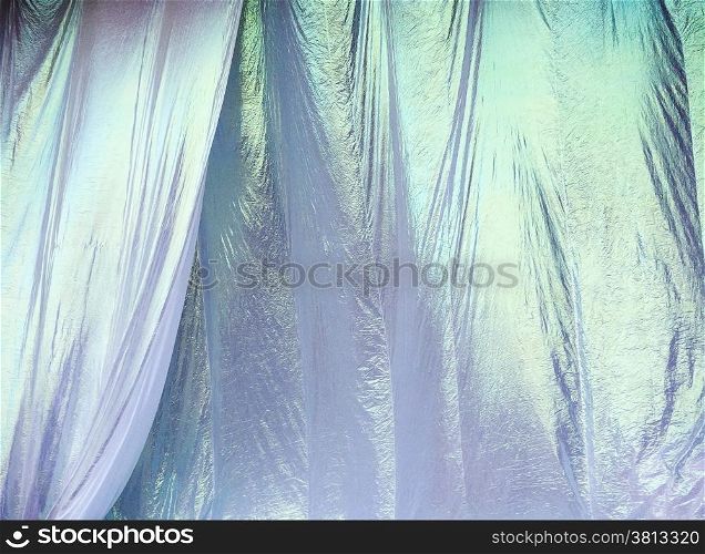 Irridescent white curtains ripple and billow in a light breeze before being pulled down at an outdoor concert.
