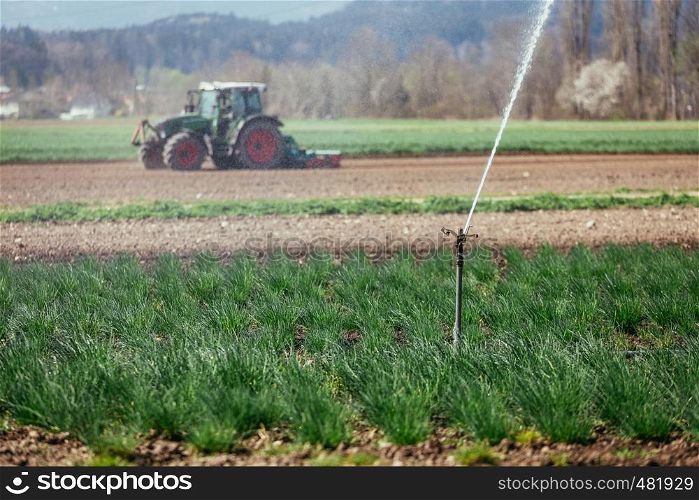 Irrigation plant on an agriculture field, tractor in the background.