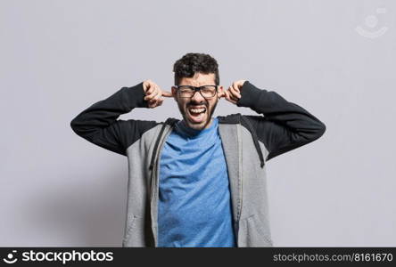 Irritated person screaming covering his ears, desperate person avoiding hearing bad news, stressed man screaming covering his ears