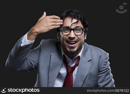 Irritated young businessman gesturing against black background