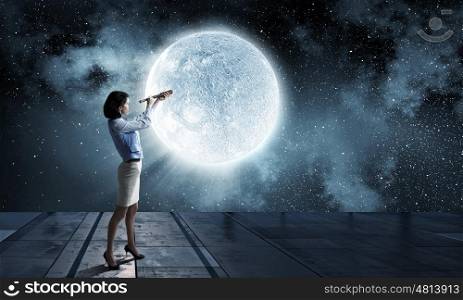 Is there life on moon. Young businesswoman looking in spyglass on full moon in sky