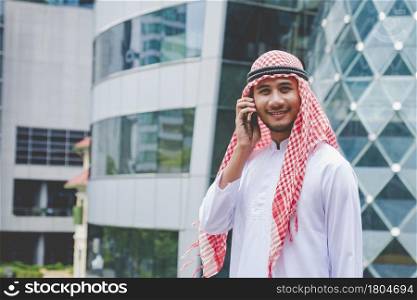 Islamic man using smartphones app organize schedule agenda focus on hands holding smartphone muslim modern uae city. Arab men wear hijab and muslim formal dress sending text sms online lifestyle
