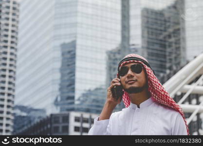 Islamic man using smartphones app organize schedule agenda focus on hands holding smartphone muslim modern uae city. Arab men wear hijab and muslim formal dress sending text sms online lifestyle