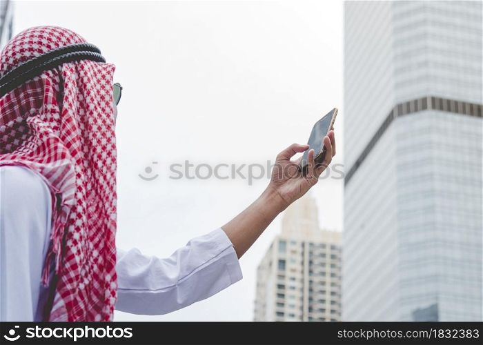 Islamic man using smartphones app organize schedule agenda focus on hands holding smartphone muslim modern uae city. Arab men wear hijab and muslim formal dress sending text sms online lifestyle