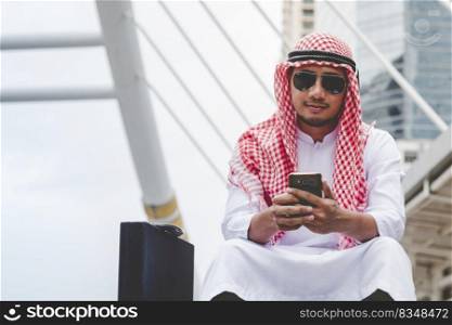 Islamic man using smartphones app organize schedule agenda  focus on hands holding smartphone muslim modern uae city. Arab men wear hijab and muslim formal dress sending text sms online lifestyle