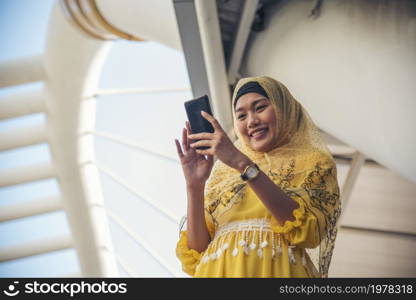 Islamic woman using smartphones app organize schedule agenda focus on hands holding smartphone muslim modern uae city. Arab woman wear hijab and muslim formal dress sending text sms online lifestyle