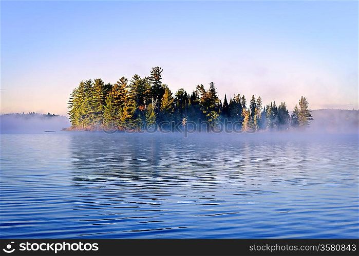 Island in lake with morning fog