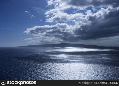 Island in Pacific ocean with puffy clouds.