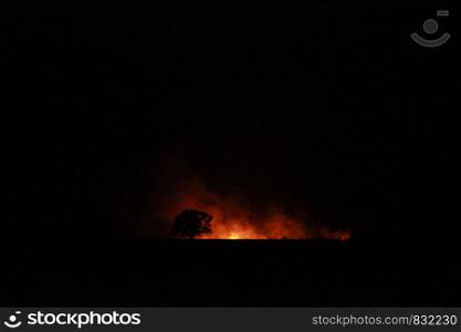 isolated bush fire blazing in the distance on a farm at night time in rural Victoria, Australia