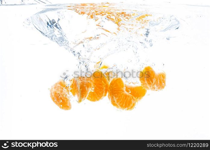 Isolated falling orange segments into water. Peeled pieces of orange fruit in the water isolated on white background. Health concept. Isolated falling orange segments into water. Peeled pieces of orange fruit in the water isolated on white background