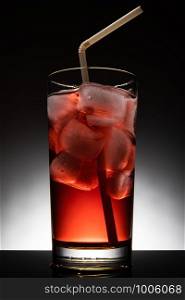 Isolated glass with a red cocktail and ice-cubes.. Isolated glass with a red cocktail and ice-cubes