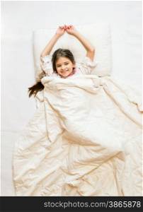 Isolated photo from high point of smiling girl lying in bed