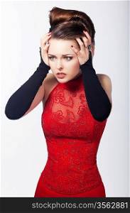 Isolated portrait of a beautiful caucasian woman in red dress. Holding her hair in astonishment
