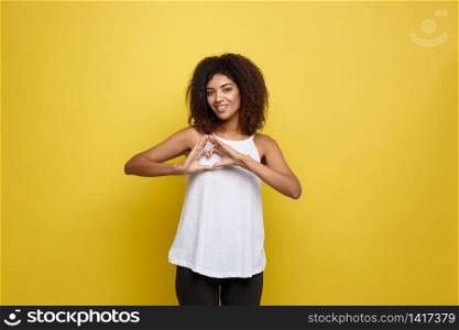 Isolated portrait of beautiful African American make heart symbol by hands. Yellow studio background. Copy Space. Isolated portrait of beautiful African American make heart symbol by hands. Yellow studio background. Copy Space.