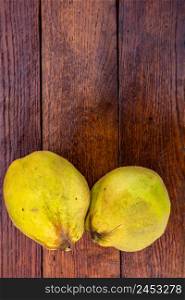 Isolated quinces. Two yellow quinces on a wooden board.