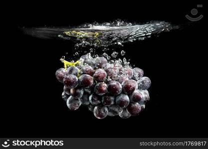 Isolated Red grapes splashing and sinking in water on black background. Isolated Red grapes splashing and sinking in water on black