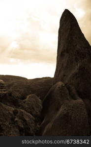 isolated rock formation with sunset landscape on background