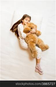 Isolated shot of cute sleeping girl hugging teddy bear