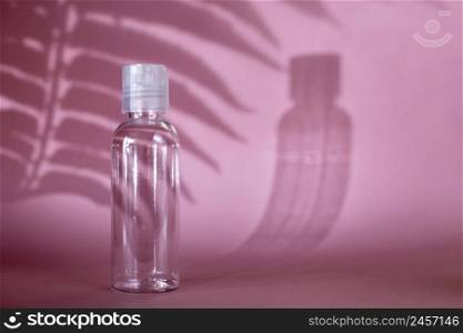 Isolated spa cosmetic products, transparent tube, branding mockup on a pink background. Plastic bottle for detergent cleaning agent. hard shadows. copy space. Isolated spa cosmetic products, transparent tube on a pink background. Plastic bottle for detergent cleaning agent.