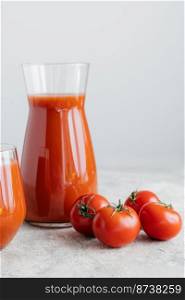 Isolated vertical shot of freshly made tomato juice, ripe tomatoes with green leaves on white background. Vegetables full of vitamins.