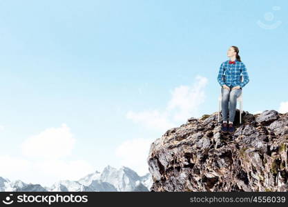 Isolation concept. Young woman in casual sitting on top of rock