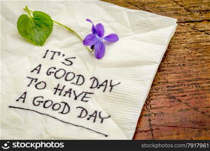 it is a good day to have a good day - handweiting on a cocktail napkin with a viola flower