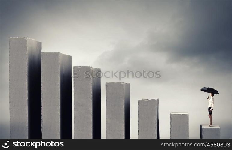It is crisis time. Young businesswoman with black umbrella standing on falling graph