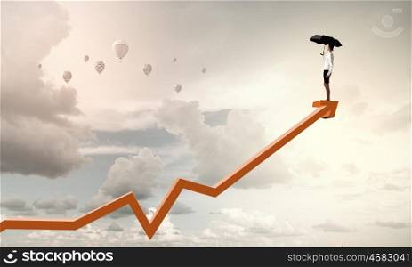 It is crisis time. Young businesswoman with black umbrella standing on graph top