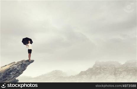 It is crisis time. Young businesswoman with black umbrella standing on top