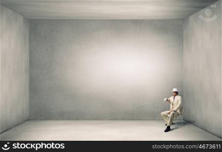 It is high time for business. Young businessman in white hat and suit in chair checking time