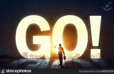It is now or never. Back view of businessman standing in light of GO word