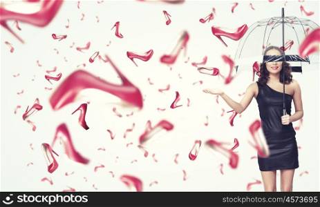 It is rainning shoes. Beautiful young woman with umbrella and falling shoes