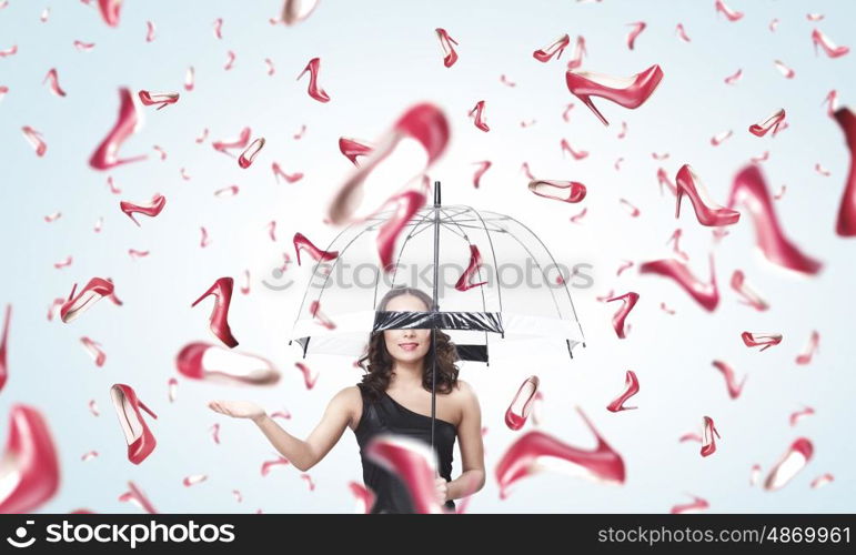 It is rainning shoes. Beautiful young woman with umbrella and falling shoes