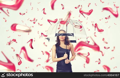 It is rainning shoes. Beautiful young woman with umbrella and falling shoes